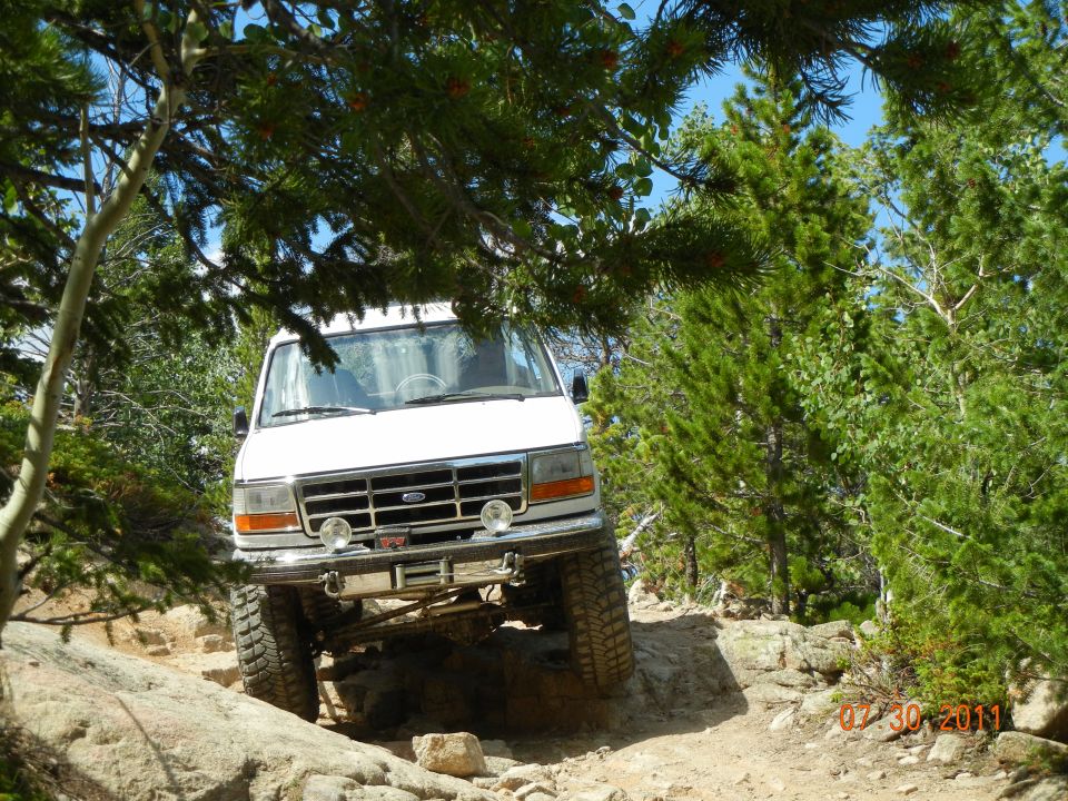 White Ford Bronco navigating a rocky off-road trail, front view