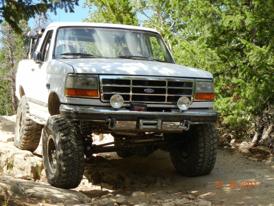 White Ford Bronco with lifted suspension and large tires on a rocky trail