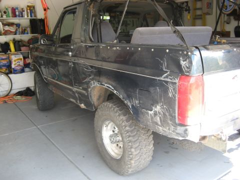 1995 Ford Bronco - This black Ford Bronco has significant body damage and appears to be in a garage.
