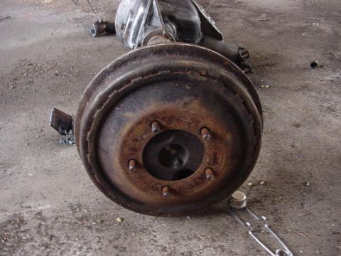 1992 Ford Bronco - Close-up of a worn rear axle assembly, likely from an older vehicle, resting on a concrete surface.