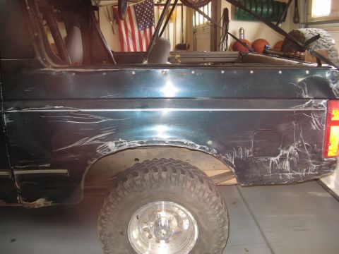 1995 Ford Bronco - This 1992 Ford Bronco shows significant damage to its side paneling, indicating a rough history.