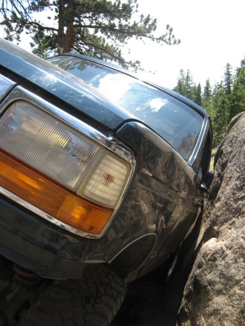 1995 Ford Bronco - This dark green SUV is stuck between two large rocks on a trail.