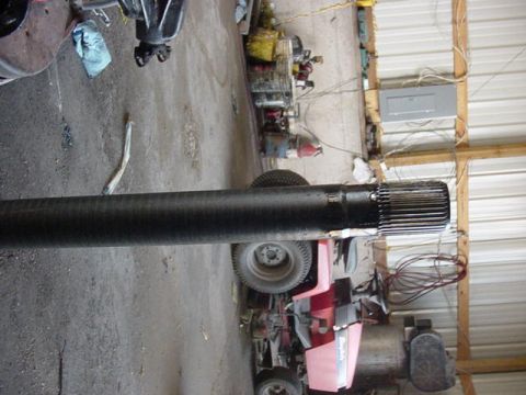 1992 Ford Bronco - A driveshaft part is shown in a garage, with other equipment in the background.