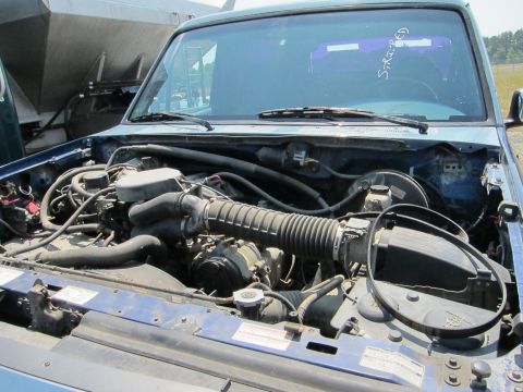 1991 Ford LTD Crown Victoria - Engine bay of a blue pickup truck, with visible hoses, belts, and engine components.