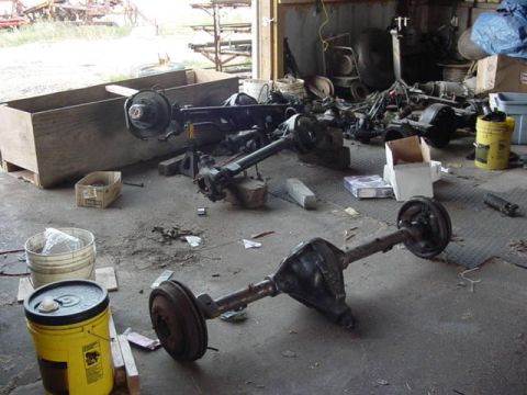 1992 Ford Bronco - Several vehicle axles are disassembled and scattered across a workshop floor.