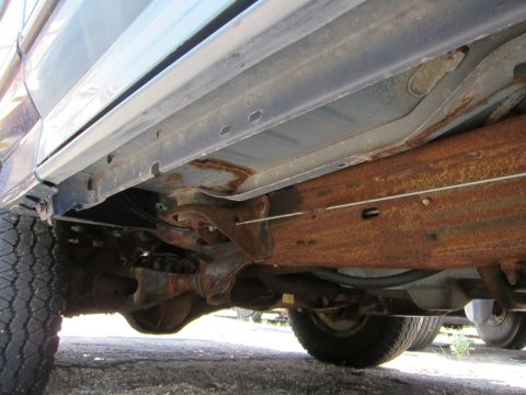 1991 Ford LTD Crown Victoria - The heavily rusted frame rails and undercarriage components are visible from a low angle.