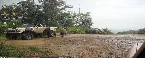 1979 Ford F-150 - Two trucks are parked in a muddy area with trees and a distant view.
