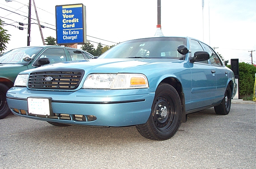 2001 Ford Crown Victoria, light blue, parked next to another car. Front grille and headlights visible