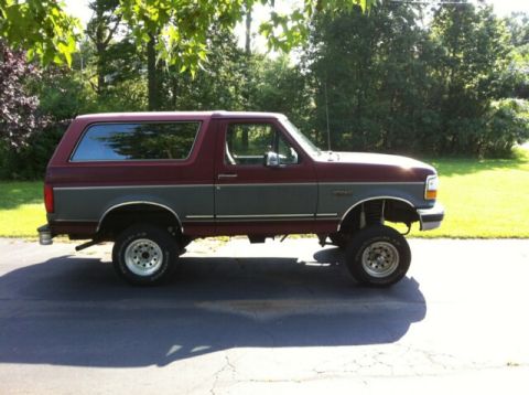 1993 Ford Bronco - Side view of a lifted 1993 Ford Bronco with two-tone paint and aftermarket wheels.