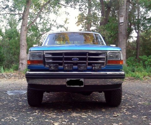 1992 Ford F-150 - Front view of a blue 1992 Ford F-150 truck parked outdoors with trees in the background.