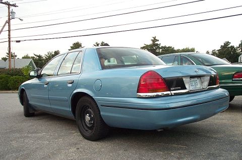 2001 Ford Crown Victoria - Rear view of a light blue 2001 Ford Crown Victoria sedan parked next to a green sedan.
