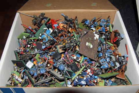 1978 Chevrolet C/K Pickup - A cardboard box overflows with a chaotic collection of miniature medieval figurines, depicting knights and soldiers in battle.