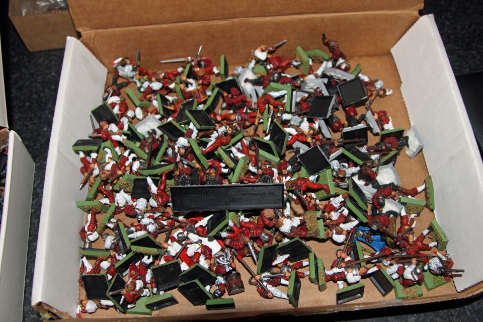 Cardboard box full of painted red-and-white wargame infantry miniatures