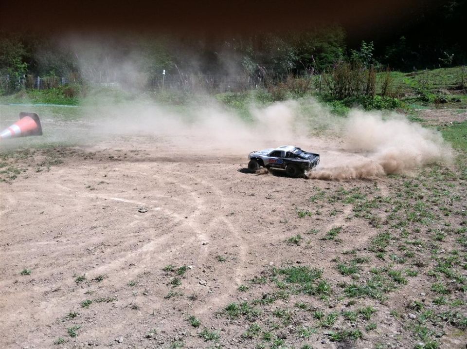 RC short-course truck spraying dust on a dirt track