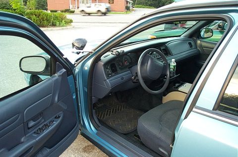 2001 Ford Crown Victoria - The interior of a 2001 Ford Crown Victoria police car is visible with the driver's door ajar.
