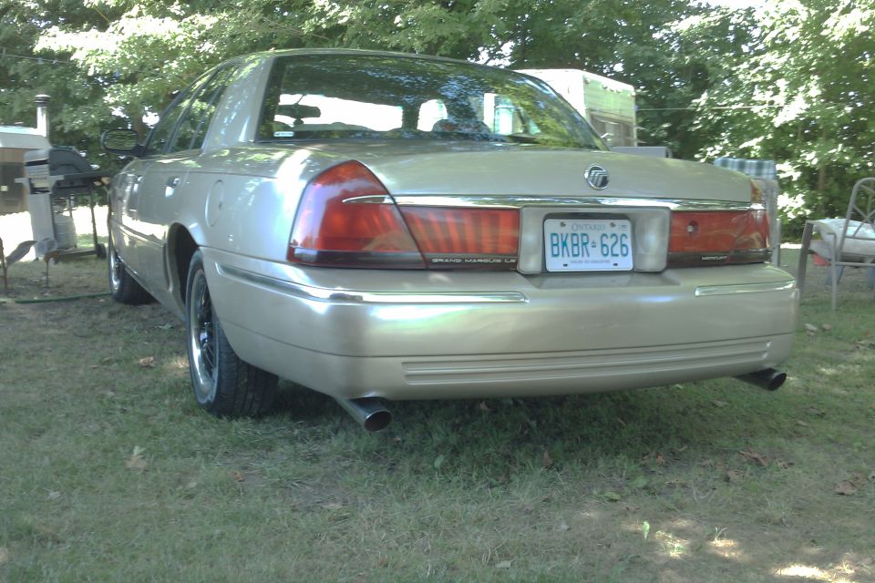 Rear view of a gold Mercury Grand Marquis with license plate BKBR-626 parked on grass