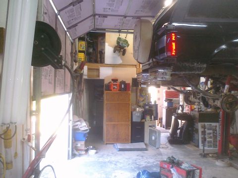1995 Ford Bronco - Rear view of a black SUV being serviced on a lift in a garage.