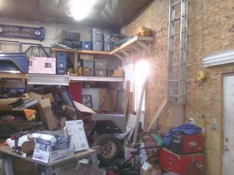 1995 Ford Bronco - A cluttered garage scene shows various vehicle parts and storage bins, with a ladder mounted on the wall.