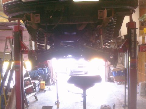 1995 Ford Bronco - The underside of a vehicle is visible as it is raised on a hydraulic lift in a workshop.