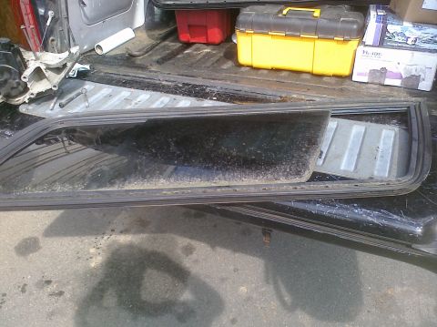 1995 Ford Bronco - A disassembled car window frame and glass are visible in the bed of a truck, alongside various tools and containers.