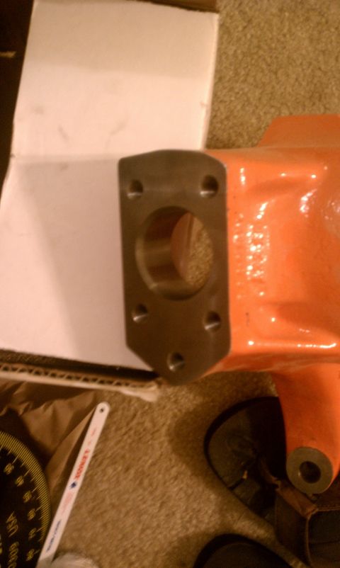 1990 Ford Bronco - A close-up of an orange metal component with a mounting flange, situated near a box and tools.