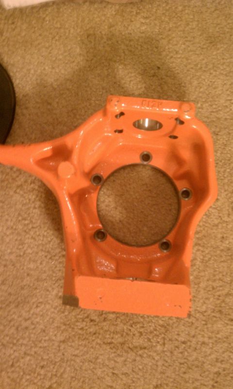 1990 Ford Bronco - This is an orange painted vehicle part, possibly a suspension component, shown against a carpeted background.