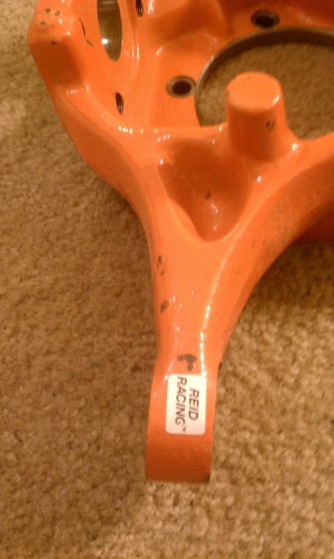 1990 Ford Bronco - Close-up of an orange suspension part with a 'REID RACING' sticker on it.