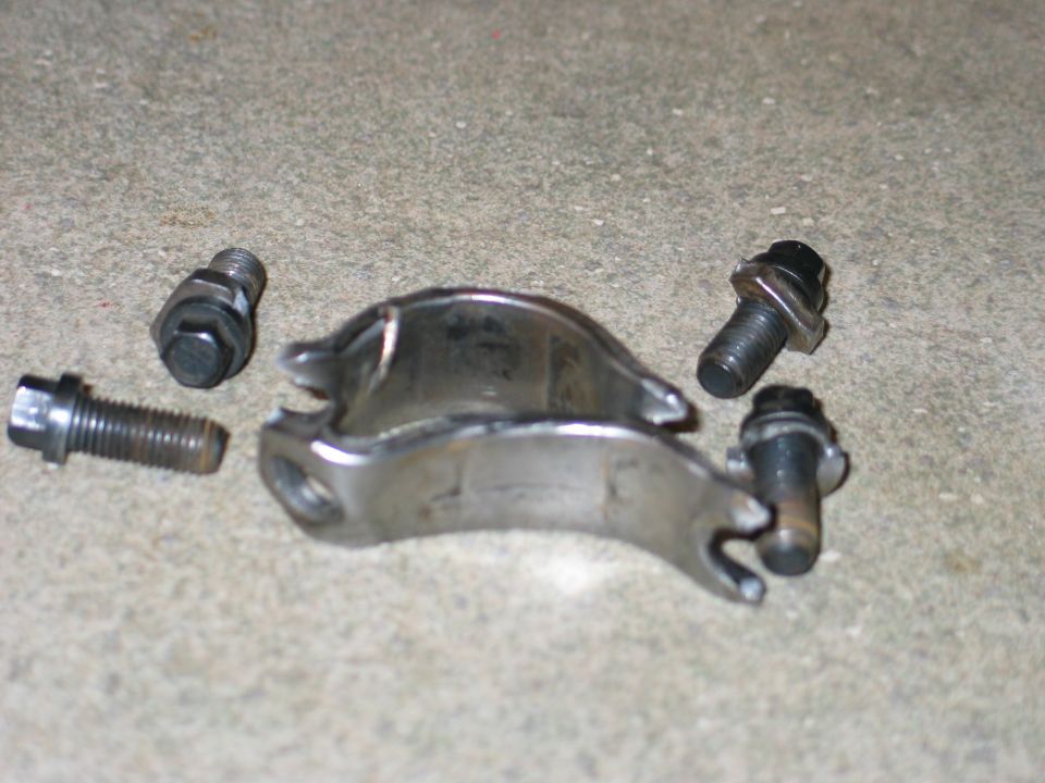 Metal bracket and four bolts on a concrete surface