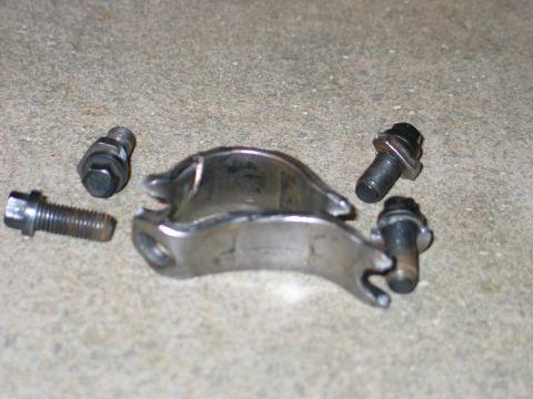 1984 Ford Bronco - A metal bracket and four bolts are shown on a concrete surface.