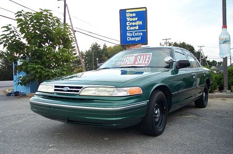 2001 Ford Crown Victoria - A green sedan is parked on asphalt with a "Use Your Credit Card" sign in the background.