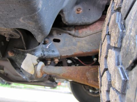 1991 Ford LTD Crown Victoria - Undercarriage view of a vehicle, focusing on suspension components and a tire.