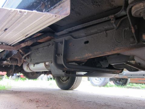 1991 Ford LTD Crown Victoria - The underside of a truck reveals its frame, exhaust system, and rear axle components.