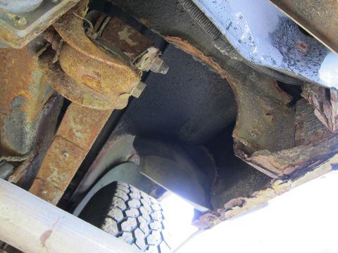 1991 Ford LTD Crown Victoria - The undercarriage of a vehicle displays significant rust and corrosion on its frame and suspension components.