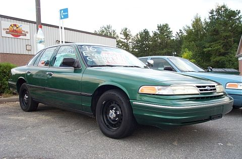 2001 Ford Crown Victoria - A green sedan, possibly a 1996 model based on windshield writing, is parked outdoors next to another vehicle.