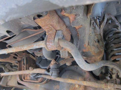 1991 Ford LTD Crown Victoria - Close-up view of heavily corroded suspension parts, including a sway bar and coil spring mount.