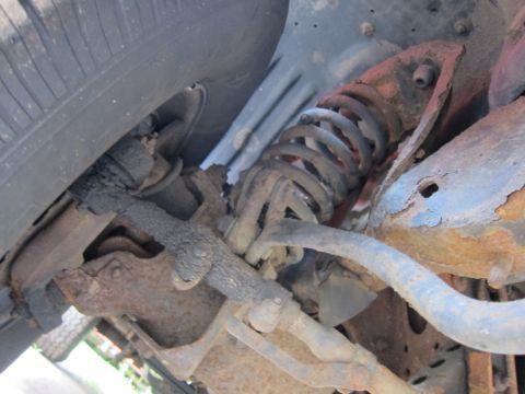 1991 Ford LTD Crown Victoria - The underside of a vehicle shows heavily rusted suspension components and a portion of the tire.