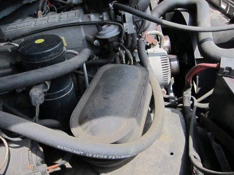 1991 Ford LTD Crown Victoria - Close-up view of engine components including hoses, alternator, and air filter housing.