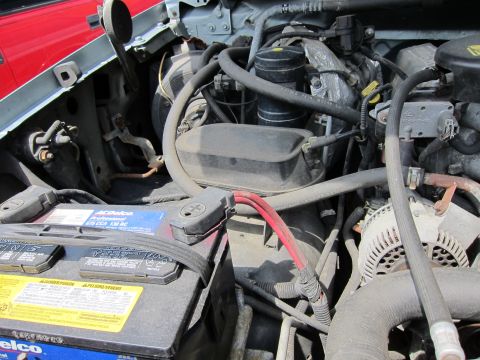 1991 Ford LTD Crown Victoria - Close-up of a vehicle's engine bay, a battery and engine parts.