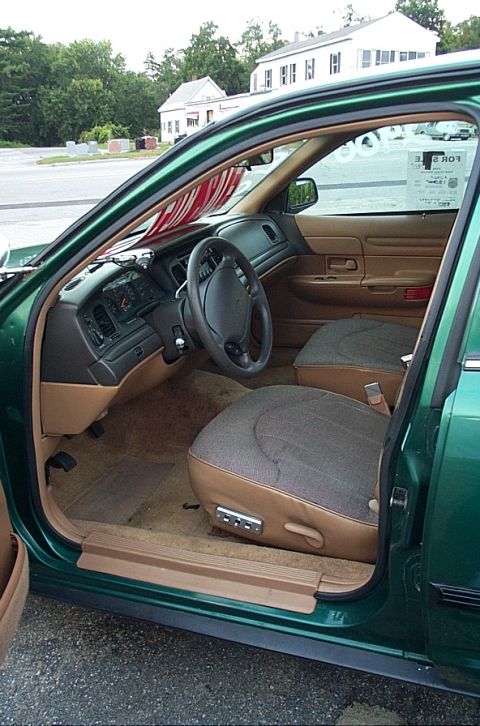 2001 Ford Crown Victoria - Interior view of a green 2001 Ford Crown Victoria, showing the dashboard, seats, and a "For Sale" sign on the windshield.