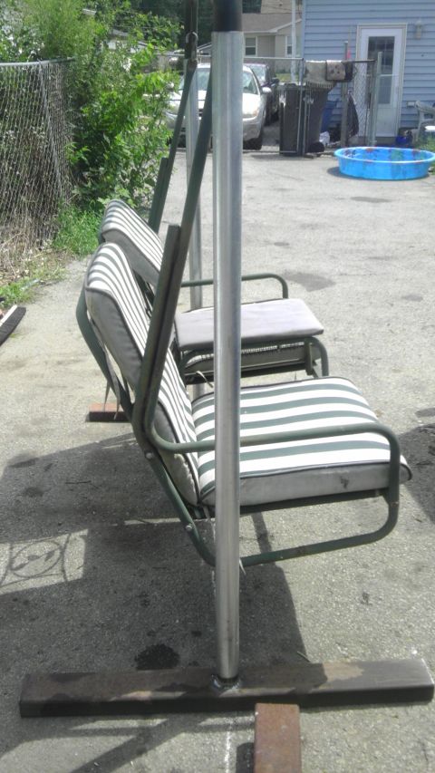 1989 Ford Bronco - A swing set with green metal frame and green and white striped cushions sits on a paved surface.