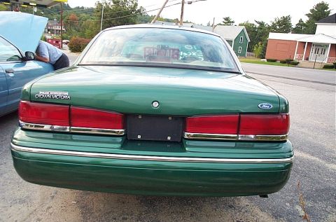2001 Ford Crown Victoria - The rear of a green 2001 Ford Crown Victoria is visible, with another vehicle in the background.