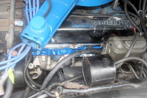 1976 Ford Ranchero - Close-up of an engine bay, showing a blue intake manifold and a valve cover with "POWER BY FORD" lettering.