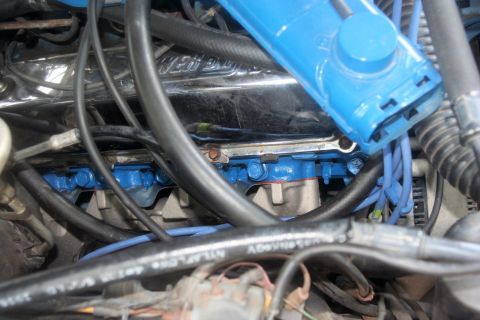 1976 Ford Ranchero - Engine bay detail with blue painted exhaust manifold and various hoses and wires.