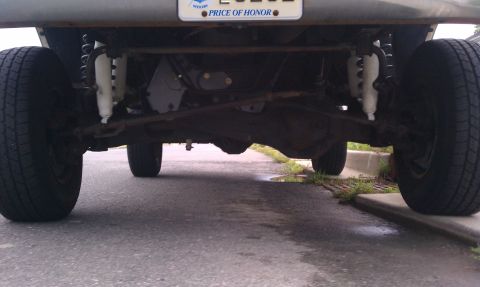 1993 Ford Bronco - Undercarriage view shows the rear axle, shocks, and tires of a vehicle.