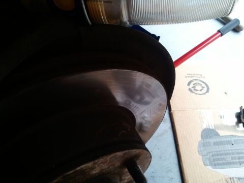 1994 Ford Bronco - Close-up of a vehicle's brake rotor and caliper assembly, with a headlight visible in the background.