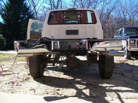1995 Ford F-150 - The rear of a white Ford truck is shown, missing its bed, with another Ford truck visible to the right.