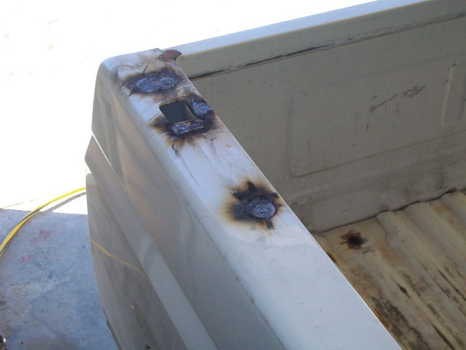 Close-up of a truck bed rail with visible welding marks and some rust