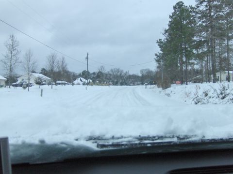 1982 Chevrolet Camaro - A residential street is covered in snow, with houses and trees visible on the sides.