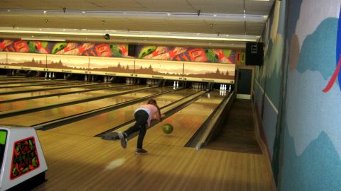 1996 Ford Bronco - A person bowls a ball down a lane in a bowling alley, aiming for the pins.