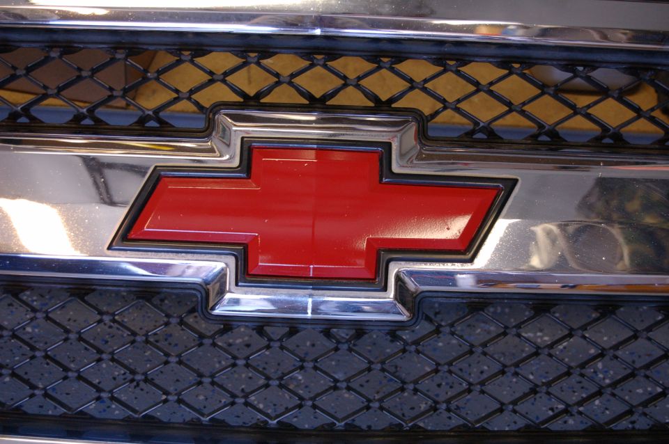 Red Chevrolet bowtie emblem on chrome grille of a 2007 Chevrolet Silverado 1500